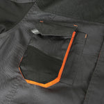 Dettaglio di una tasca di una giacca da lavoro grigia e nera con bordi arancioni, realizzata in tessuto resistente. Ideale per abbigliamento da lavoro, abbigliamento protettivo, abbigliamento tecnico. Tasche multifunzione per attrezzi e accessori.