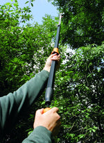 Persona che utilizza un potatore telescopico per tagliare rami alti in un giardino. Strumento per la potatura di alberi e arbusti, ideale per giardinaggio e manutenzione del verde. Manico ergonomico e lama affilata per tagli precisi e sicuri.