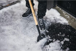 Rimozione della neve con pala Fiskars su vialetto ghiacciato, attrezzo da giardino con manico in legno e punta in metallo, scarpe invernali nere, attrezzatura per la pulizia della neve, strumenti per l'inverno, sicurezza invernale.