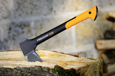 Ascia Fiskars X11 appoggiata su ceppo, manico arancione e nero