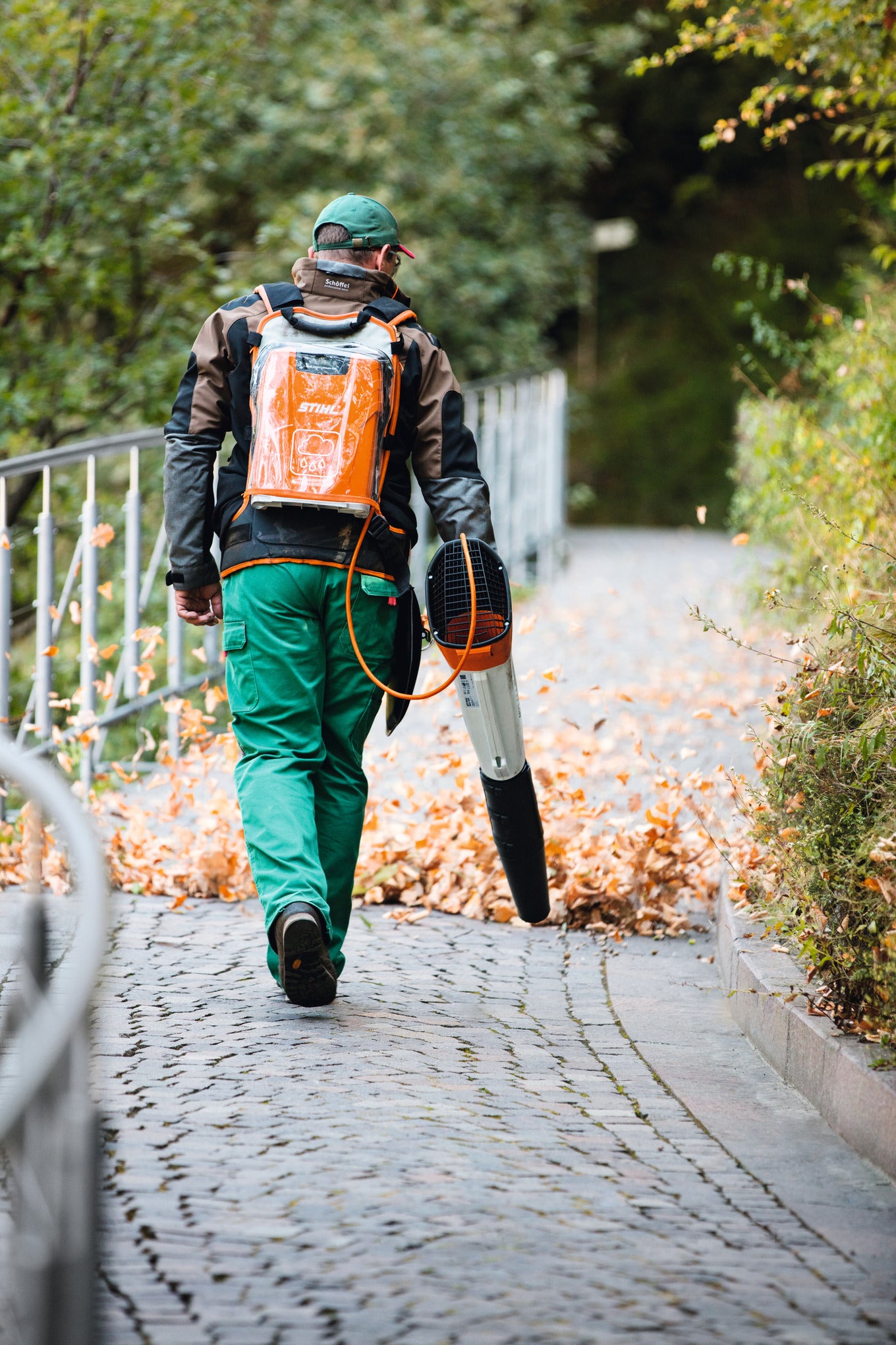 Operatore con soffiatore a batteria STIHL BGA 100 e batteria a zaino durante pulizia foglie