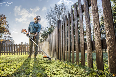 Operatore al lavoro con decespugliatore Stihl FS 94 RC-E per rifinitura del bordo prato