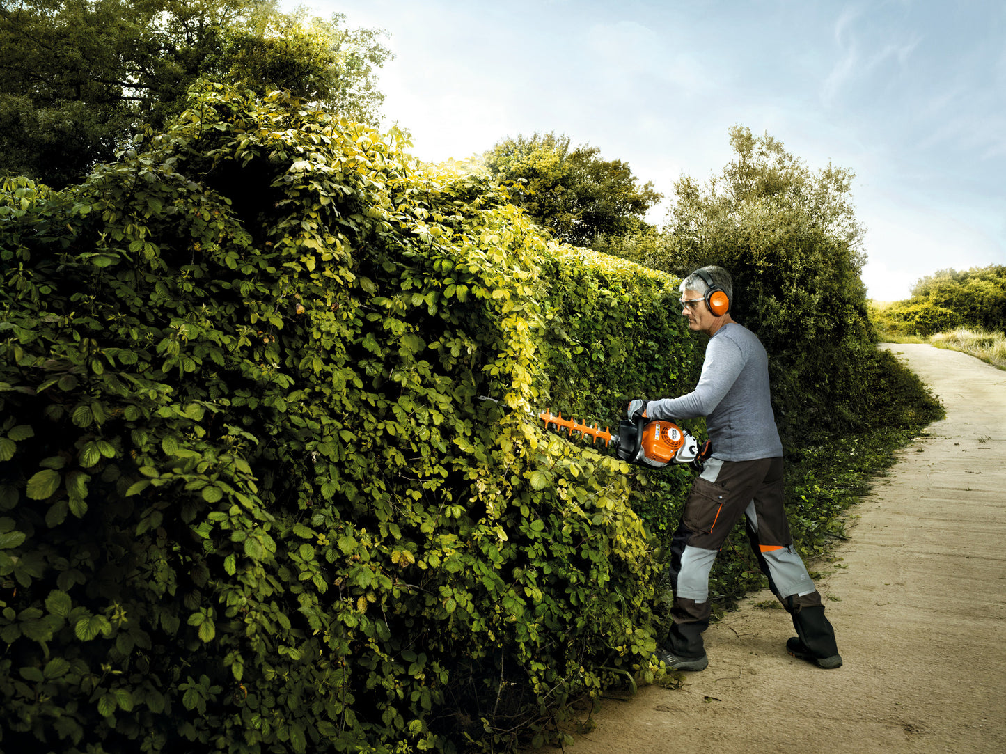 Operatore al lavoro con tosasiepi a scoppio STIHL HS 82 R su siepe