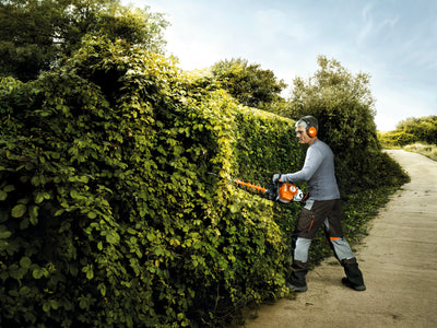 Operatore al lavoro con tosasiepi a scoppio STIHL HS 82 R su siepe