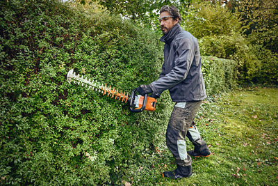 Operatore con pantaloni protettivi STIHL HS MULTI-PROTECT durante lavoro con tosasiepi