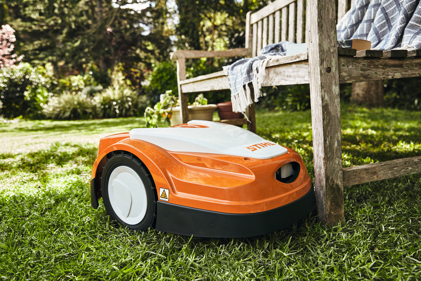 Robot tosaerba STIHL iMOW RMI 422 P vicino a panchina in giardino