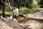 Rullo spazzola STIHL KW-MM in uso per pulizia di vialetti e marciapiedi